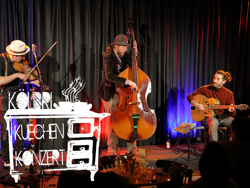 Band als Trio auf der Bühne, mit Geige, Contrabass und Gitarre.