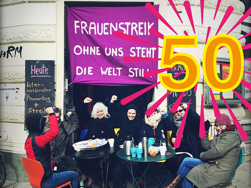 Frauen vorm Kölibri. Über der Tür hängt ein Transpi mit dem Text: Frauenstreik - ohne uns steht die Welt still