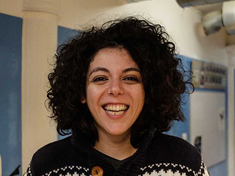 Carmen hat dunkle Locken und lächelt in die Kamera