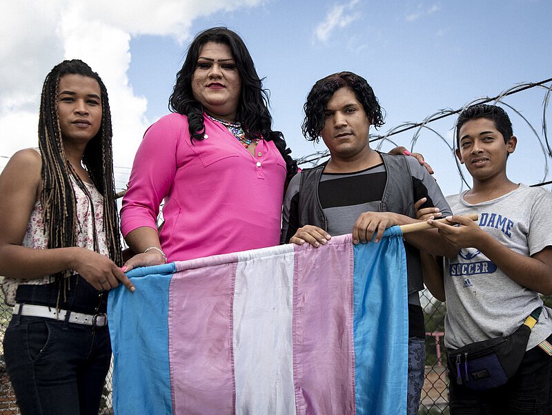 4 queere Personen halten die Transgender Fahne