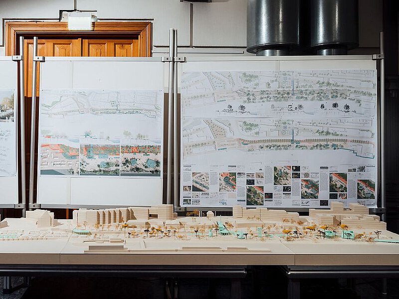 Das Holzmodell des Entwurfs steht vor Infotafeln