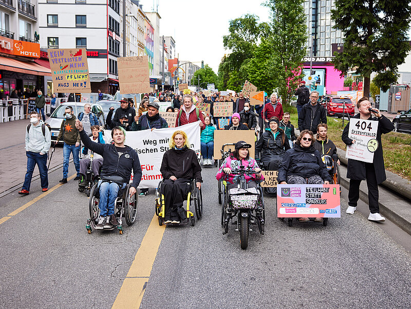Ein bunter Demo-Zug mit vielen Rollifahrer*innen